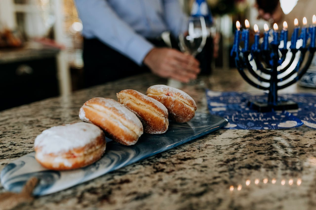 A Hanukkah setup with sufganiyot, menorah, and wine, celebrating in a cozy indoor setting.